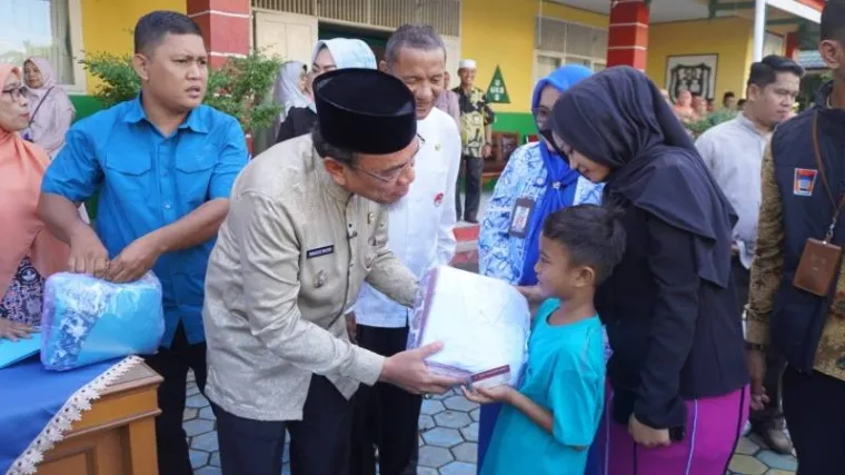 Wawako Padang, Maigus Nasir saat menyerahkan seragam gratis kepada salah satu siswa. (foto: Diskominfo Padang)