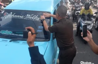 Kajari Padang, Dr Aliansyah menempelkan stiker ke kendaraan yang lewat di depan kantor Kejari Padang, Selasa (22/7/2025) (Foto:DI)