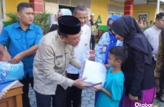 Wawako Padang, Maigus Nasir saat menyerahkan seragam gratis kepada salah satu siswa. (foto: Diskominfo Padang)